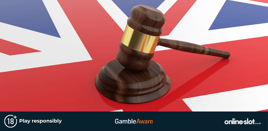 A wooden judge's gavel and sound block resting on a glossy surface featuring the United Kingdom’s Union Jack flag